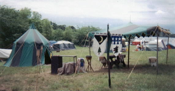 Aurthour & Cassy's medieval camp: A green & black striped round pavilion & shade fly; banners displaying our heraldic devices