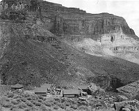 DETAIL OF EARLY HERMIT CAMP. MAIN LODGE AND CABINS, TONTO PLATEAU. NO TREES - MULES IN. THE TONTO TRAIL (ON THE WAY TO BOUCHER) IS SEEN BEYOND. CIRCA 1913. NPS. 