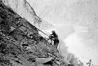 RIVER TRAIL CONSTRUCTION BY CCC ENROLLEES. MAN USING JACKHAMMER ON STEEP SLOPE. CIRCA 1934. NPS. 
