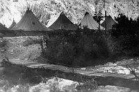 TENTS OF CCC CAMP 818 BY PHANTOM RANCH AS SEEN FROM ACROSS  BRIGHT ANGEL CREEK. WOODEN FOOTBRIDGE CROSSING CREEK IN FOREGROUND. CIRCA 1935. PURVIS. 